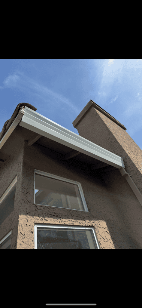 Sheet metal gutter installation on modern home's roof.