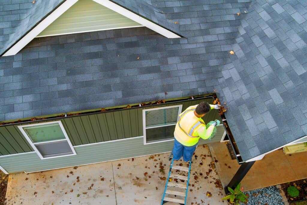 Metal roof with shingles being inspected by a worker on a ladder.